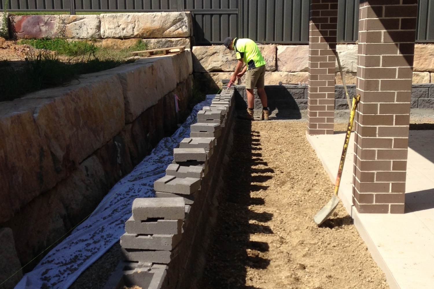 Marc Peterson from Novascape Landscaping glueing capping blocks on a segmental block retaining wall in Cooranbong